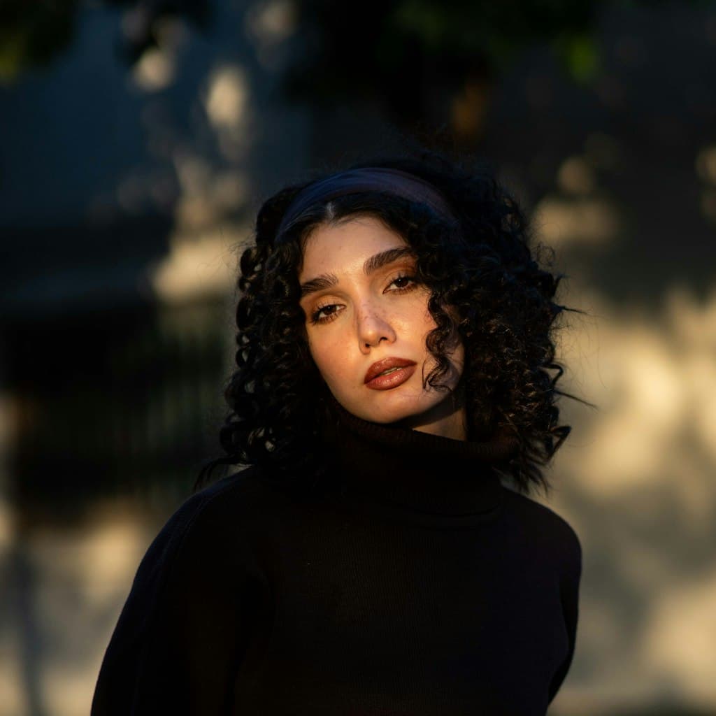 Portrait photo of young woman with dark curly hair used as source for caricature comparison