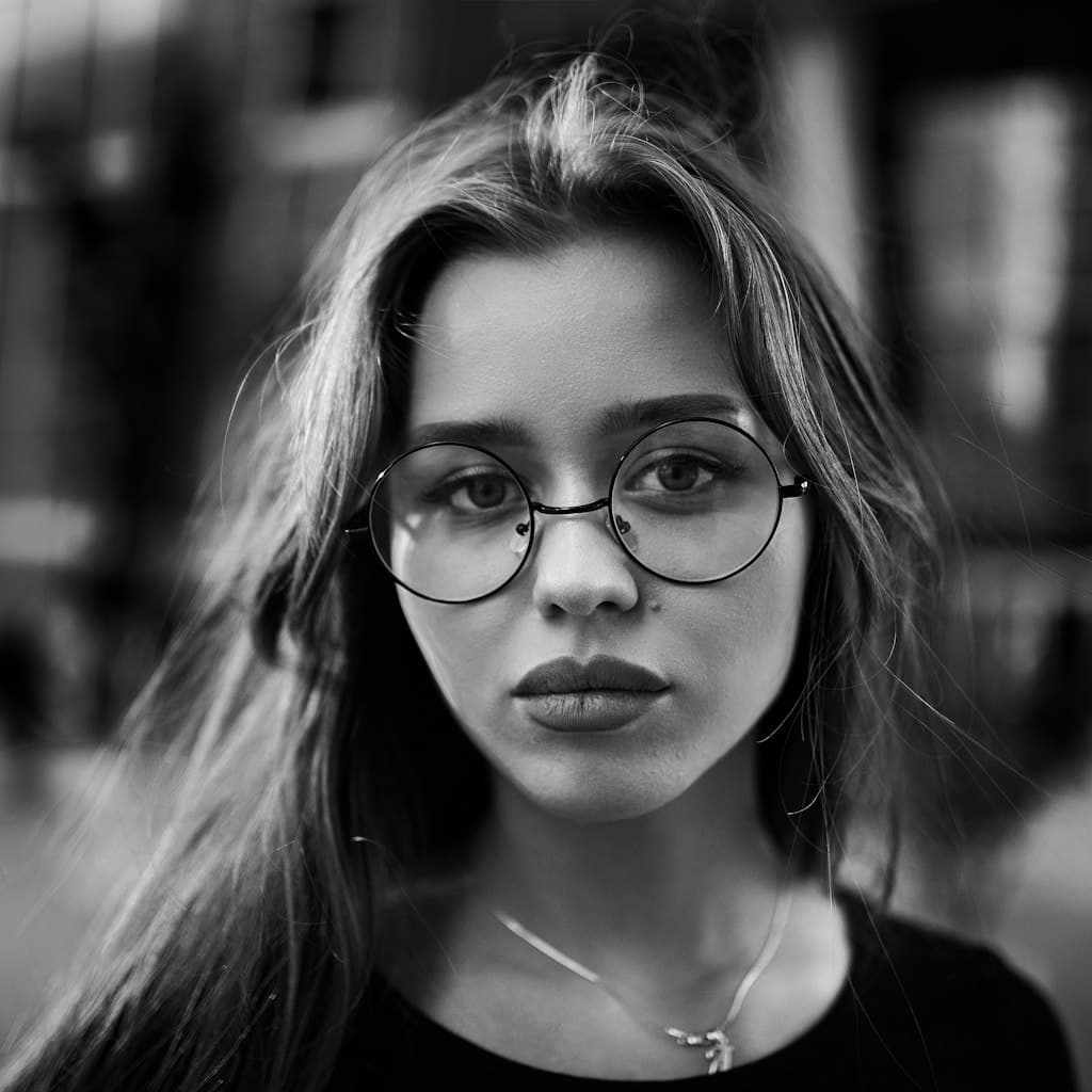 Portrait photo of woman in her 30s with round glasses used as source for caricature comparison